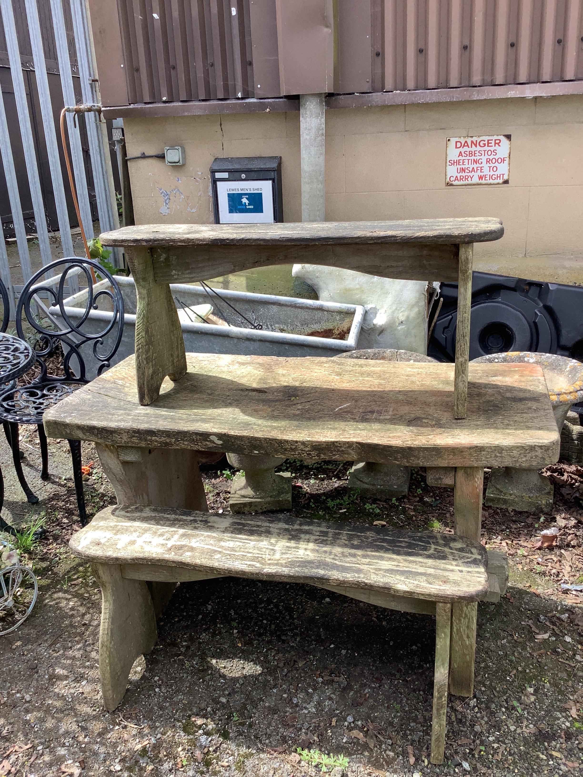 A rustic style rectangular elm garden table, width 122cm, depth 54cm, height 68cm together with a pair of bench seats